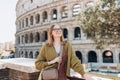 A happy blond woman tourist is standing near the Coliseum, old ruins at the center of Rome, Italy. Concept of traveling Royalty Free Stock Photo