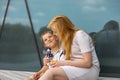 Happy blond woman and little boy sitting on terrace and eating sweets. Mother and son enjoy time together. Positive