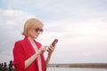 Happy blonde caucasian girl in sunglasses and a pink jacket on a background of river shore. Royalty Free Stock Photo