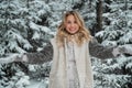 Happy blonde girl with blue eyes throws snow flakes from her hands. Beautiful portrait with bokeh in the winter forest.