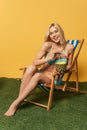 Happy blonde girl in swimsuit resting in deck chair