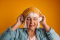 Happy blonde hair 50s woman dancing to the rhythm of the melody, listening to the song in wireless headphones Royalty Free Stock Photo