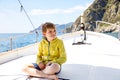 Happy blonde kid boy enjoying sailing boat trip. Family vacations on ocean or sea on sunny day. Healthy beautiful school Royalty Free Stock Photo