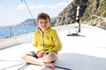 Happy blonde kid boy enjoying sailing boat trip. Family vacations on ocean or sea on sunny day. Healthy beautiful school Royalty Free Stock Photo