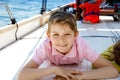 Happy blonde kid boy enjoying sailing boat trip. Family vacations on ocean or sea on sunny day. Healthy beautiful school