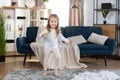 Happy blonde little 3 years old child girl, having fun, jumping and dancing indoors in a sunny light living room at home Royalty Free Stock Photo