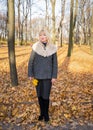 Happy blonde mature woman is standing in autumn park and thinking. Beautiful woman is relaxing in nature on sunny day. Portrait of Royalty Free Stock Photo