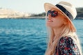 Happy blonde Mediterranean woman in hat amazed by panorama on sea