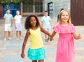 Happy blonde preteen girl walking with african american girl playmate Royalty Free Stock Photo