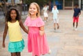 Happy blonde preteen girl walking with african american girl playmate