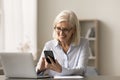 Happy blonde retired senior business woman typing on mobile phone Royalty Free Stock Photo