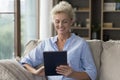Happy blonde senior lady holding tablet computer at home Royalty Free Stock Photo