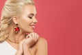 Happy blonde woman with fashion golden earring on colorful pink background, profile portrait Royalty Free Stock Photo