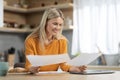 Happy blonde woman freelancer working from home, reading papers Royalty Free Stock Photo