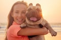 Happy blonde woman with french bulldog on india goa beach at sunset