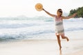 Happy blonde woman with hat in hand, enjoys her tropical vacation at beach, in Seychelles