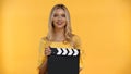 Happy blonde woman holding clapboard and Royalty Free Stock Photo