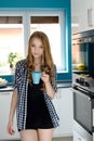 Happy blonde woman holding a cup of coffee in her kitchen Royalty Free Stock Photo