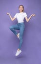 Happy Blonde Woman Jumping Posing In Mid-Air, Purple Background, Vertical Royalty Free Stock Photo