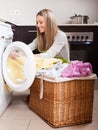 Happy blonde woman loading clothes into washing machine Royalty Free Stock Photo