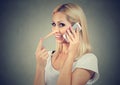 Happy blonde woman with long nose talking on mobile phone telling lies. Liar concept.