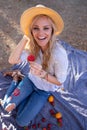 Happy blonde woman at picnic holding strawberry and laughing