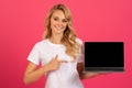 Happy blonde woman pointing at laptop with empty screen, studio Royalty Free Stock Photo