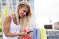 Happy blonde woman shopping and using mobile phone smiling outdo Royalty Free Stock Photo