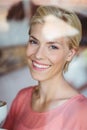 Happy blonde woman smiling at camera and holding a cup of coffee Royalty Free Stock Photo