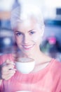 Happy blonde woman smiling at camera and holding a cup of coffee Royalty Free Stock Photo