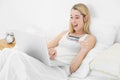 Happy blonde woman using her laptop for home shopping lying on h Royalty Free Stock Photo