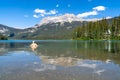 Happy blonde woman wades and swims in Emerald Lake in Yoho National Park, British Columbia on a sunny summer day