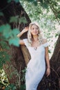Happy blonde woman in white summer dress walks in park. Fashion
