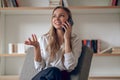 Blonde young woman caller talking on the phone at home telephone in living room. Royalty Free Stock Photo