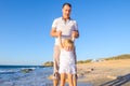 Happy blondy child girl with her father holding hands and having fun walking on the beach. Family vacation, travel concept. Bright