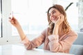 Happy blondy woman in blouse sitting by the table