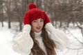 Happy blue-eyed girl in knitted red hat and mittens and woolen sweater in winter forest. Female knitwear Royalty Free Stock Photo