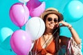 Happy bohemian girl standing with helium balloons