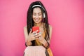 Happy bohemian influencer woman listening playlist music with pink background - Focus on face