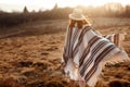 Happy boho woman, walking towards sun, wearing hat and poncho at