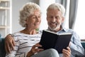 Happy bonding elderly senior retired family couple reading paper book.
