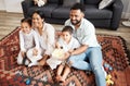 Happy, bonding family quality time at home with parents watching a movie and having snacks on the floor. Young couple Royalty Free Stock Photo