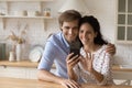 Happy bonding millennial family couple using smartphone.