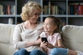 Happy bonding older mature grandmother using smartphone with granddaughter. Royalty Free Stock Photo