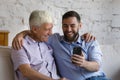 Happy bonding two male generations family using cellphone. Royalty Free Stock Photo