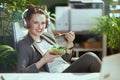 happy bookkeeper woman in green office eating salad