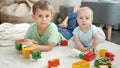 Happy boy with baby brother building house from colorful toy bricks and blocks. Concept of children development Royalty Free Stock Photo