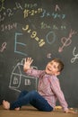 Happy boy on the background of a school board showing five fingers