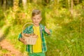 Happy boy with basket of mushrooms in autumn forest showing thumbs up Royalty Free Stock Photo