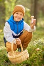 Happy boy with basket picking mushrooms in forest Royalty Free Stock Photo